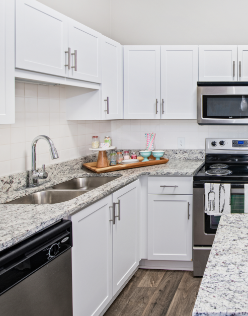 Modern kitchen with white cabinets, granite countertops and updated appliances at MAA Oglethorpe luxury apartments in Atlanta, GA
