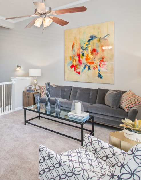 Modern-style model living room with colorful wall art and grey couch at MAA Oglethorpe luxury apartments in Atlanta, GA