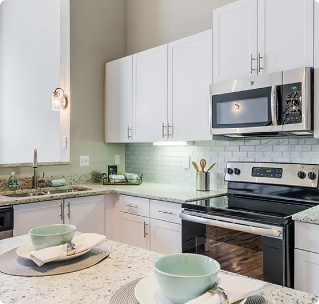 Modern apartment kitchen with white cabinets, upgraded appliances and light countertops at MAA Piedmont Park luxury apartments in Atlanta, GA