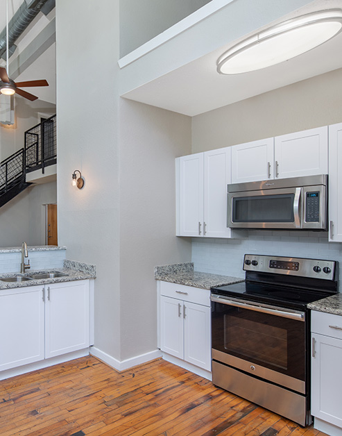 Modern kitchen with white cabinets, tile backsplash, stainless steel appliances and light countertops with wood floors at MAA Piedmont Park luxury apartments in Atlanta, GA