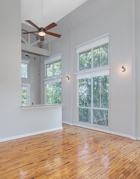 Spacious empty living room with 10-foot ceilings and a ceiling fan, large picture windows on hard wood floors at MAA Piedmont Park luxury apartments in Atlanta, GA