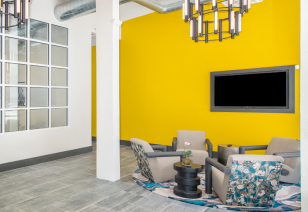 Clubhouse with yellow wall and sitting area with wall-mounted TV at MAA Piedmont Park luxury apartments in Atlanta, GA