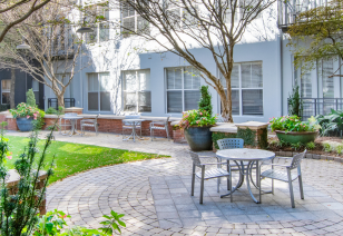 Grassy common area with shady patio tables and chairs at MAA Piedmont Park luxury apartments in Atlanta, GA