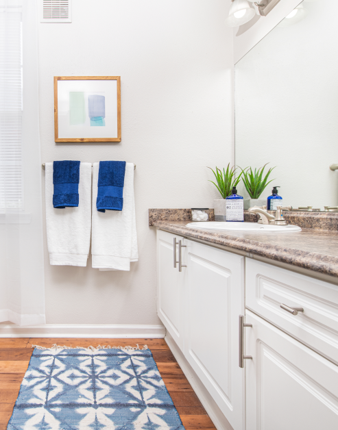 Bathroom with modern designed white cabinets, single sink and vanity and wood floors at MAA Pleasant Hill luxury apartments in Duluth, GA