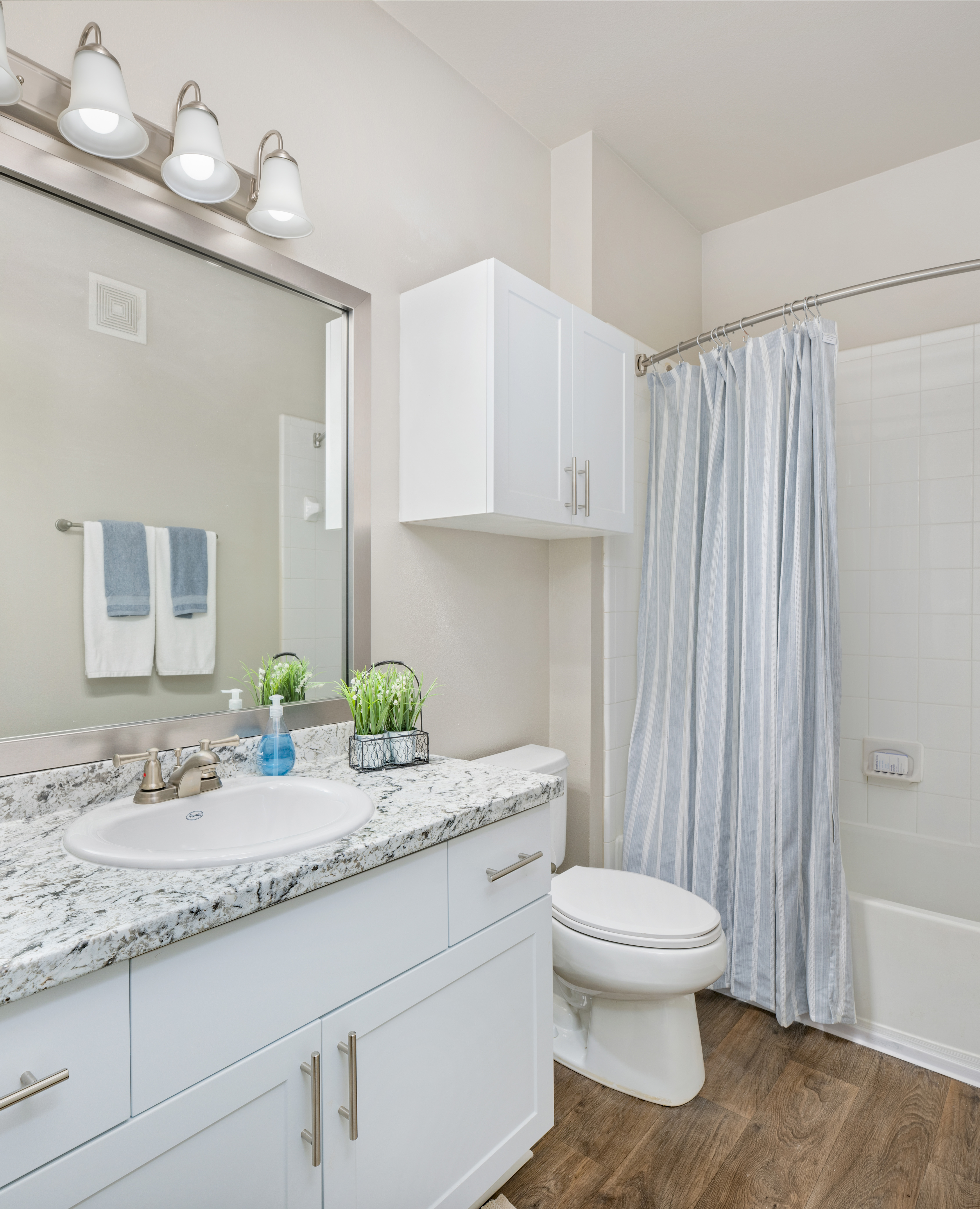 Modern bathroom with grey marble countertop, single vanity with sink, white cabinets next to shower curtains at MAA Prescott luxury apartments in Duluth, GA