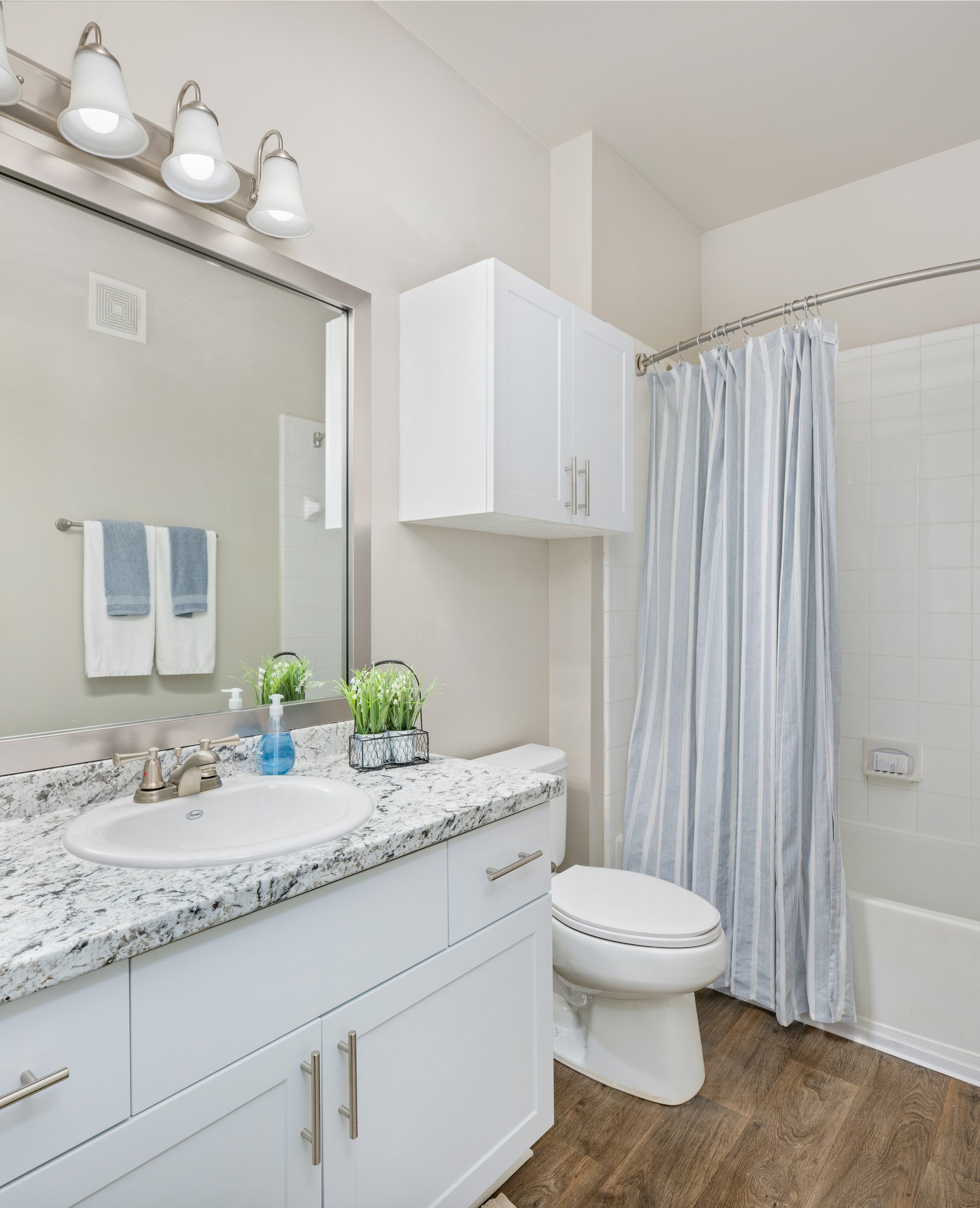 Modern bathroom with grey marble countertop, single vanity with sink, white cabinets next to shower curtains at MAA Prescott luxury apartments in Duluth, GA