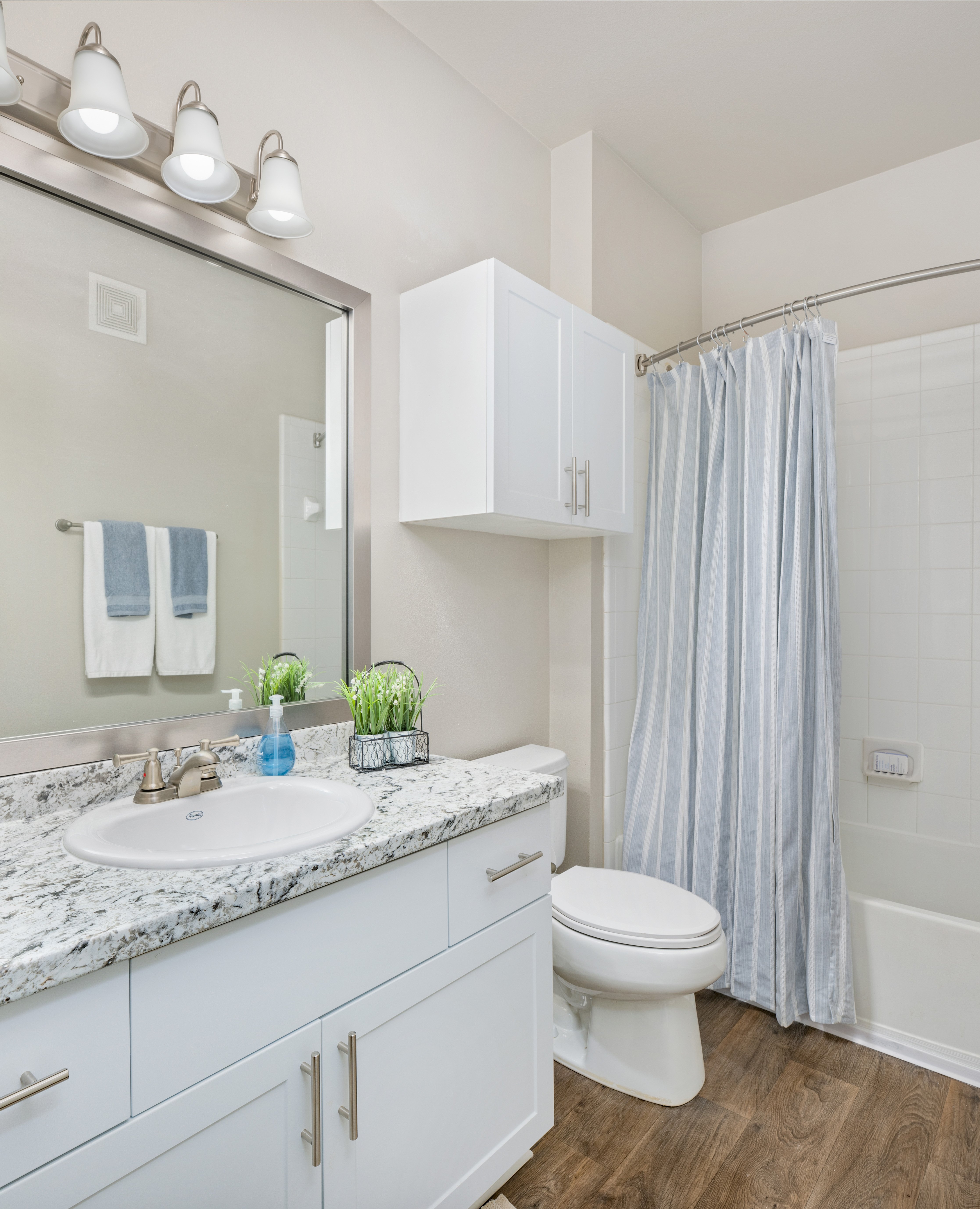 Modern bathroom with grey marble countertop, single vanity with sink, white cabinets next to shower curtains at MAA Prescott luxury apartments in Duluth, GA