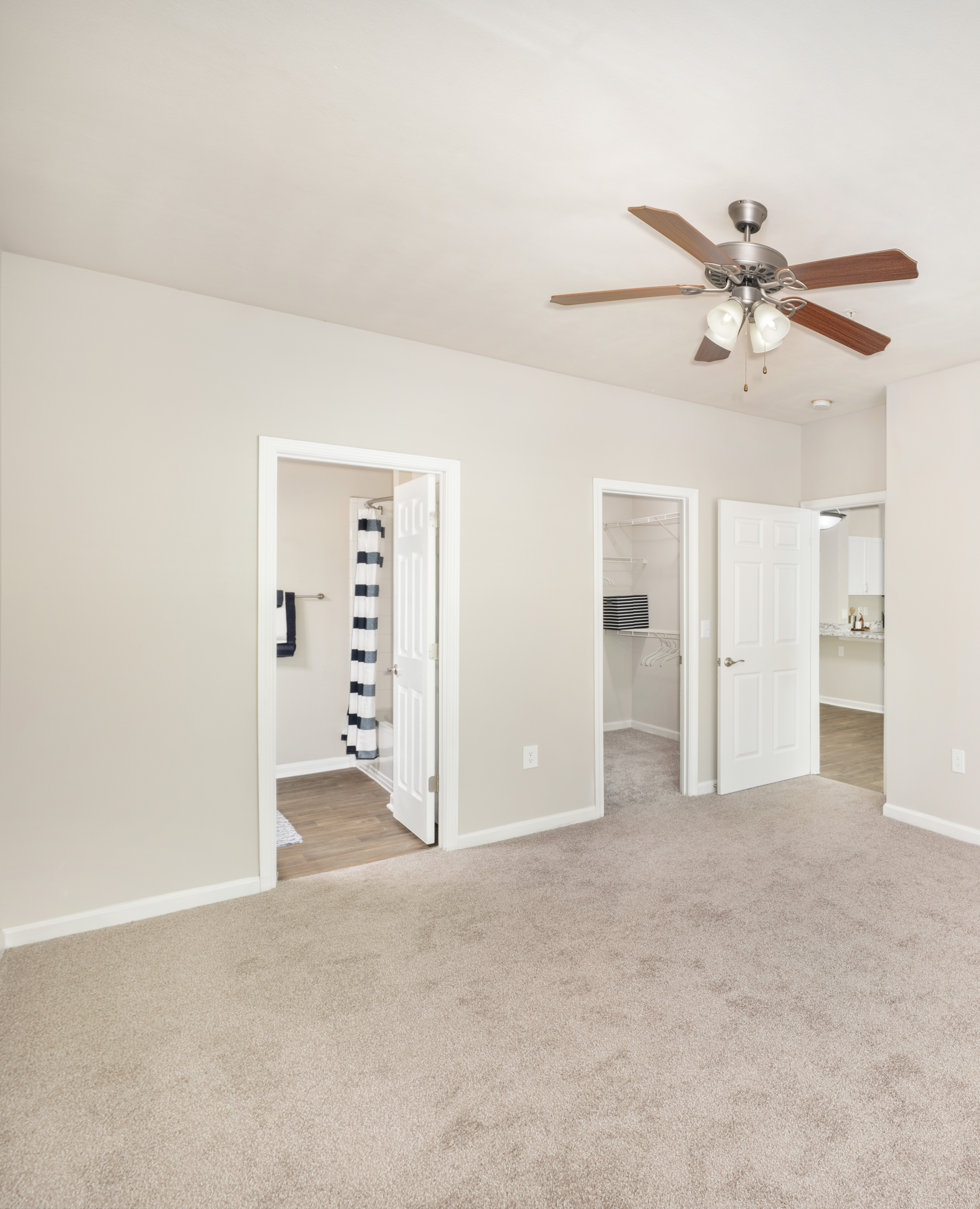 Spacious empty master bedroom with a ceiling fan, en suite bathroom and a walk-in closet at MAA Prescott luxury apartments in Duluth, GA