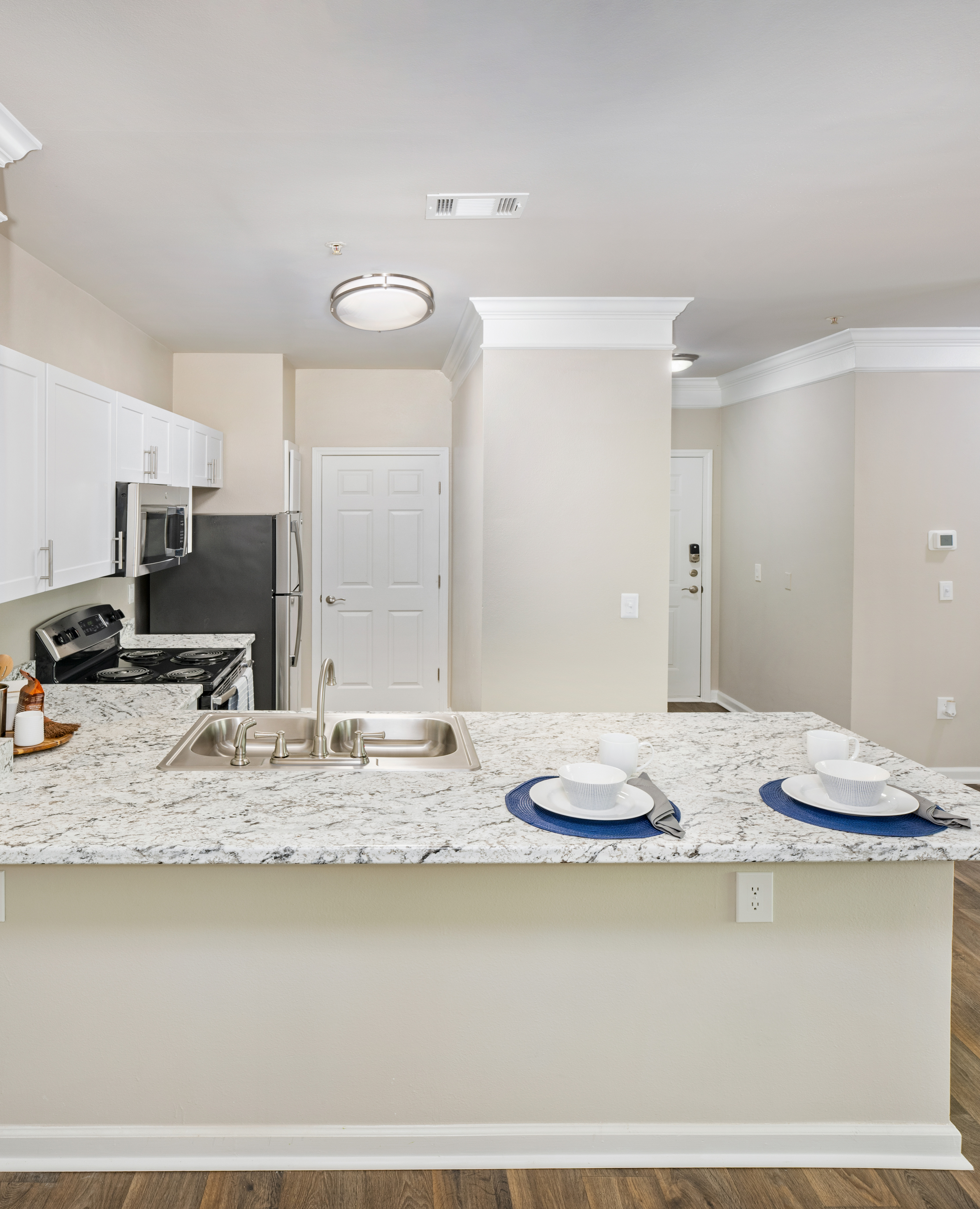 Front view of modern kitchen with granite countertops, white cabinets and stainless steel appliances at MAA Prescott luxury apartments in Duluth, GA