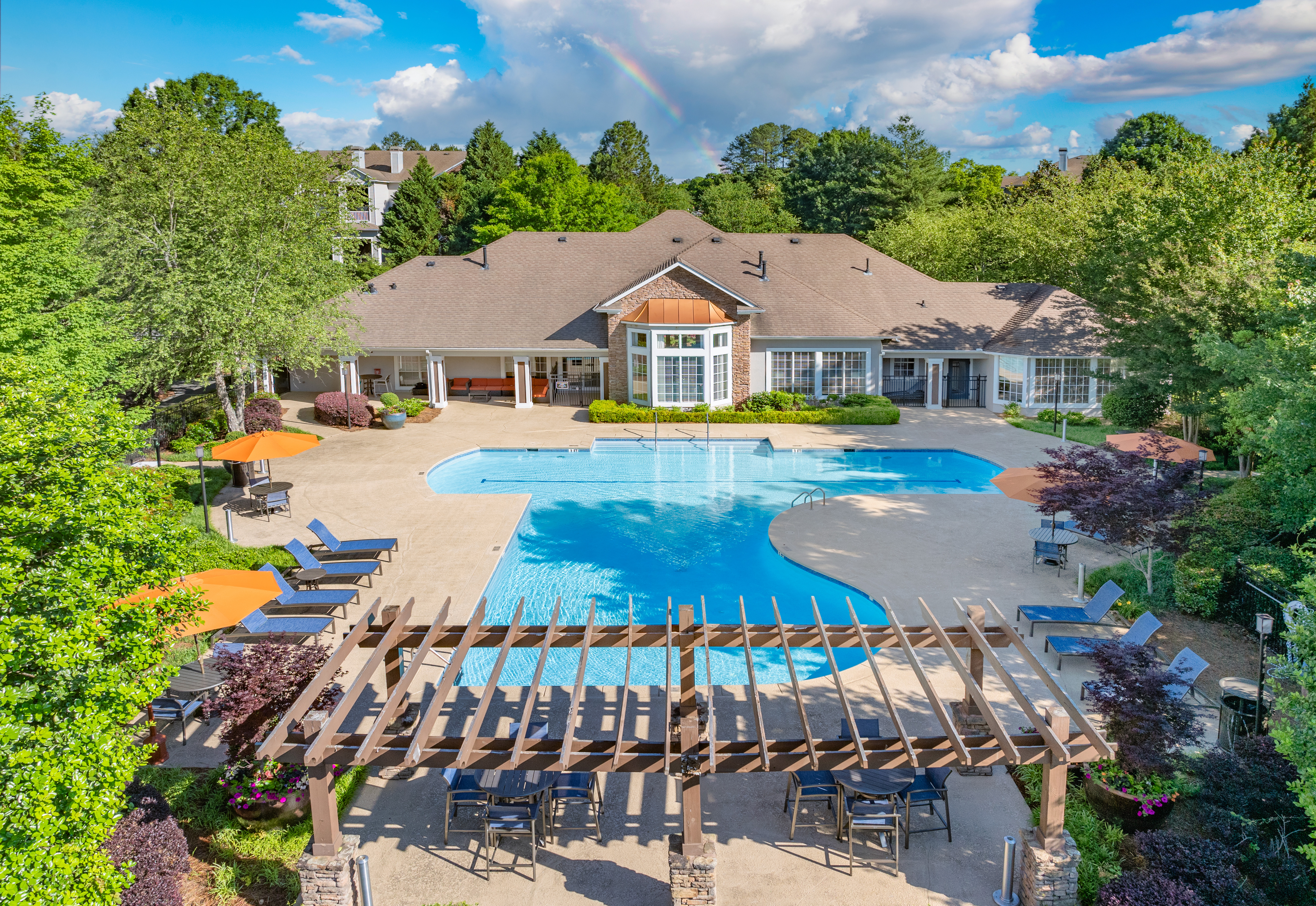 Wide view of swimming pool with a wooden pergola across from a clubhouse at MAA Prescott luxury apartments in Duluth, GA