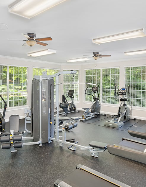 Community fitness center with ceiling fans, weight machines and treadmills with picture window views at MAA Prescott luxury apartments in Duluth, GA