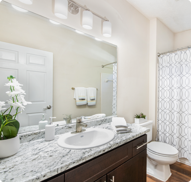 Modern bathroom with brown cabinets and light grey marble countertop at MAA River Oaks luxury apartments in Duluth, GA