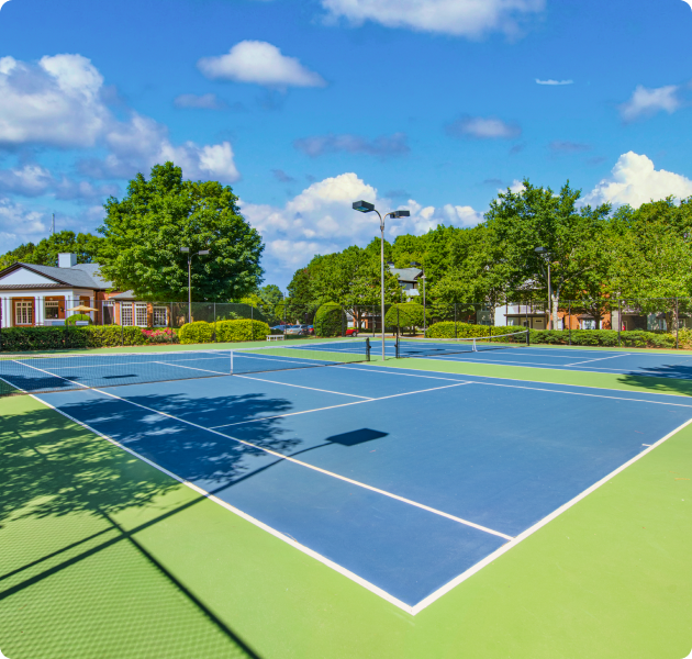 Community tennis courts surrounded by lush trees at MAA River Oaks luxury apartments in Duluth, GA