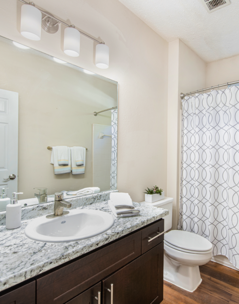 Stylish modern bathroom with brown cabinets and large vanity mirror and sink at MAA River Oaks luxury apartments in Duluth, GA