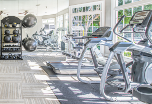 Community fitness center with treadmills next to picture window views at MAA River Oaks luxury apartments in Duluth, GA