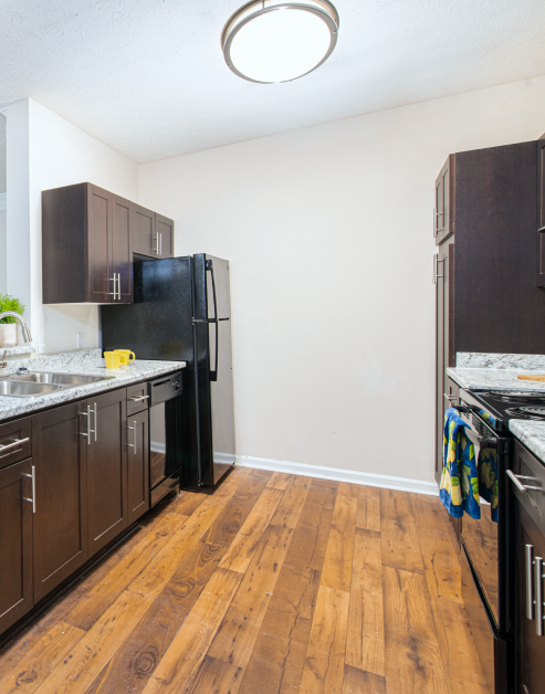 Upscale kitchen with stylish hard floors, dark wood cabinets and upgraded appliances at MAA River Oaks luxury apartments in Duluth, GA