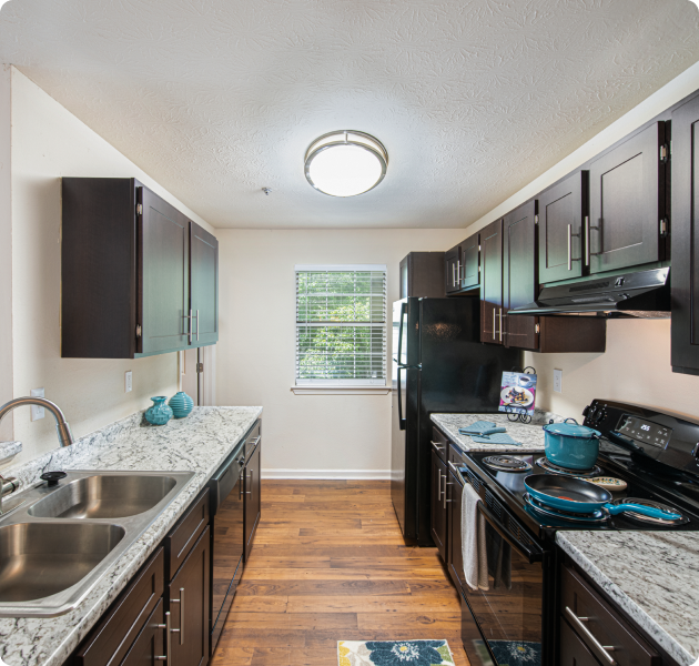 Spacious kitchen with dark cabinets, hard wood floors and granite countertops at MAA River Place luxury apartments in Duluth, GA