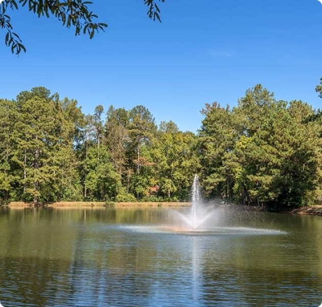 Peaceful lake with a water fountain at MAA River Place luxury apartments in Duluth, GA