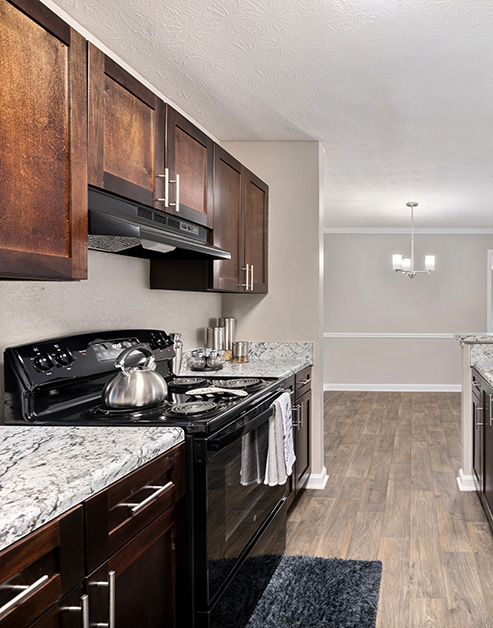 Modern kitchen with dark cabinets, granite countertops, upgraded appliances on wood floors at MAA River Place luxury apartments in Duluth, GA