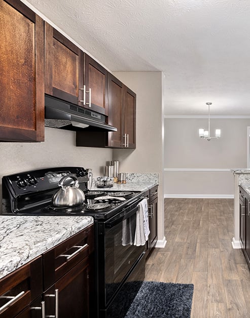 Modern kitchen with dark cabinets, granite countertops, upgraded appliances on wood floors at MAA River Place luxury apartments in Duluth, GA