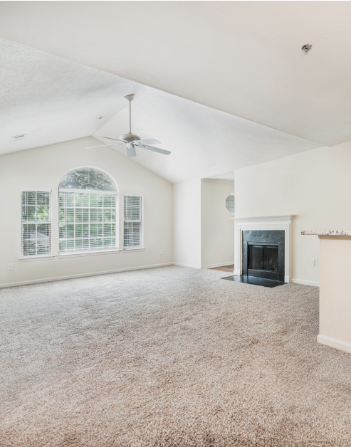 Spacious carpeted living room space with vaulted ceilings and fireplace at MAA River Place luxury apartments in Duluth, GA