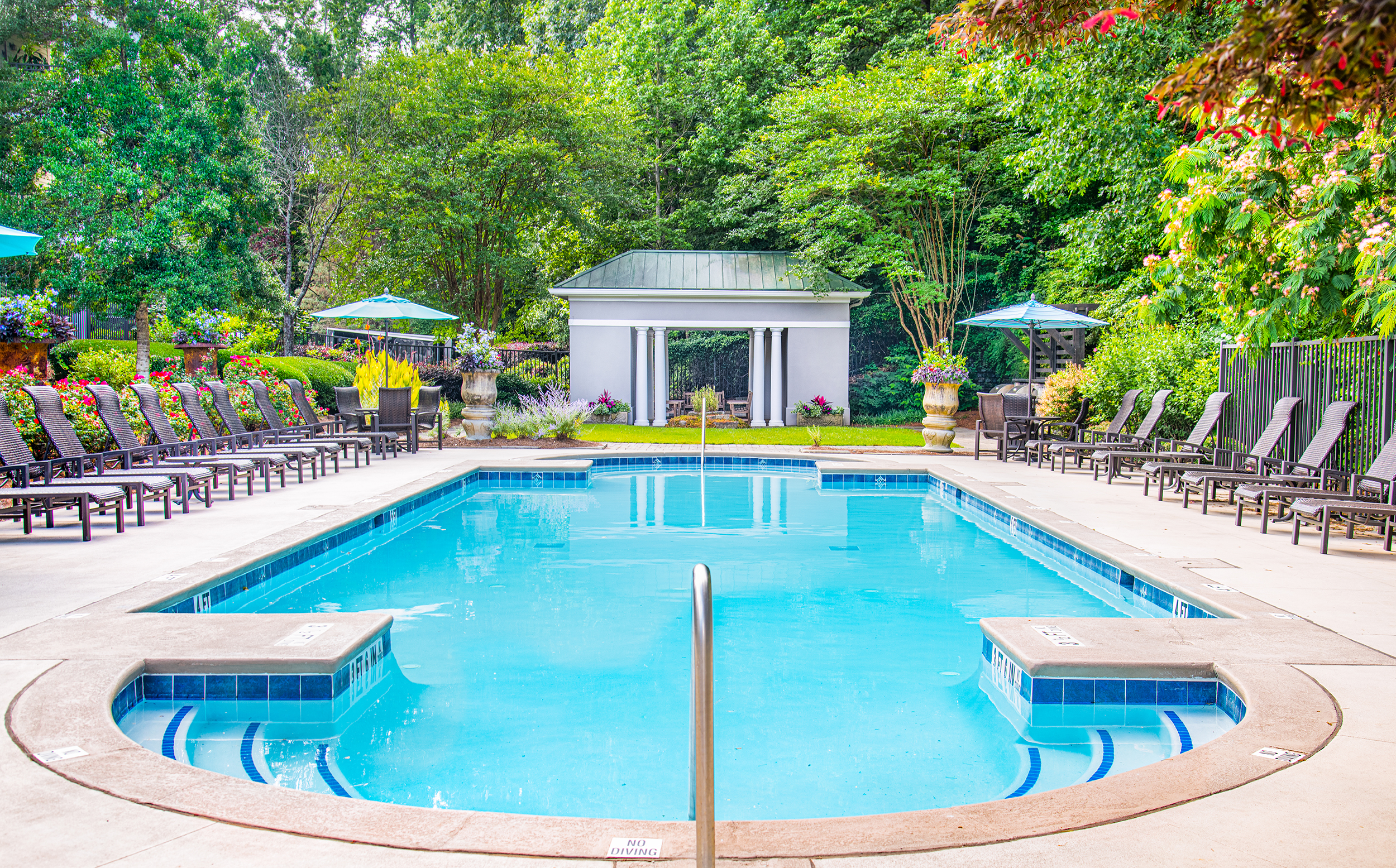 Swimming pool with lounge chairs surrounded by lush greenery at MAA Riverside luxury apartments in Atlanta, GA