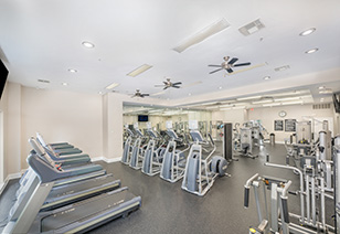 Wide view of fitness center with ceiling fans and rows of workout machines at MAA Riverside luxury apartments in Atlanta, GA