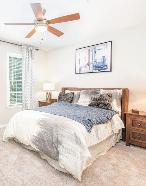 Spacious bedroom with natural filtered light and rustic wood bed set at MAA Riverside luxury apartments in Atlanta, GA