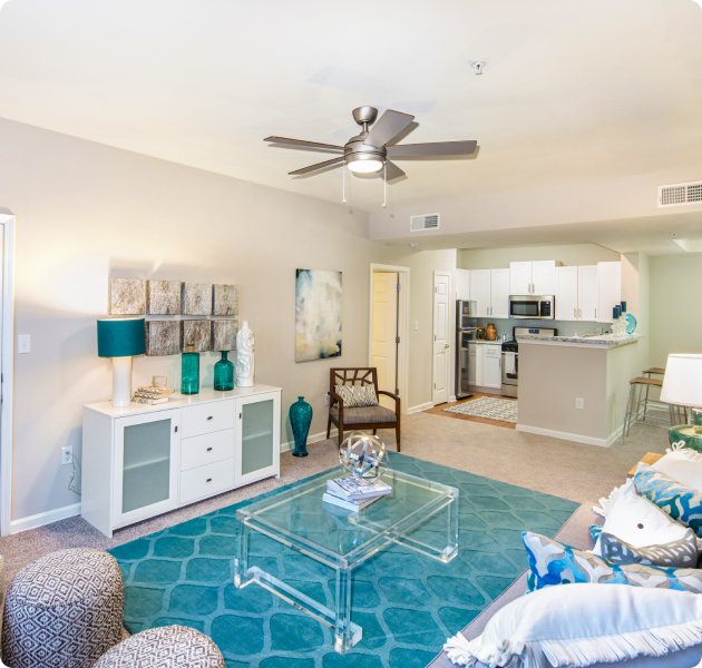 Spacious model living room with blue area rug, ceiling fan and white furniture at MAA Spring luxury apartments in Smyrna, GA