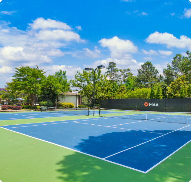 Community tennis courts with lighting surrounded by trees at MAA Spring luxury apartments in Smyrna, GA