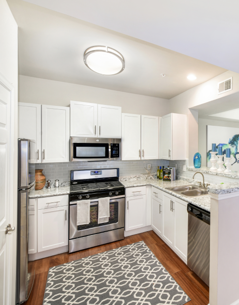 Model upscale kitchen with area rug, hard wood floors, and white cabinets at MAA Spring luxury apartments in Smyrna, GA