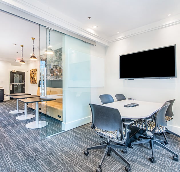 Community business center conference room with glass doors and multiple work sitting areas with booth seating and tables at MAA Stratford luxury apartments in Atlanta, GA