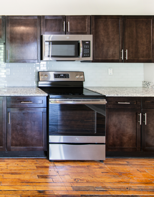 Open kitchen with dark brown cabinets, reclaimed wood floors and upgraded appliances at MAA Stratford luxury apartments in Atlanta, GA