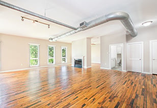 Spacious empty living room area with exposed duct system and multiple windows on glossy wood floors at MAA Stratford luxury apartments in Atlanta, GA