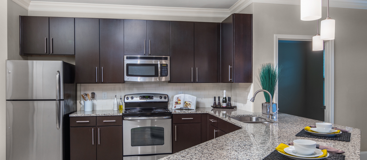 Open kitchen with stainless steel appliances and granite countertops at MAA West Village luxury apartments in Smyrna, GA