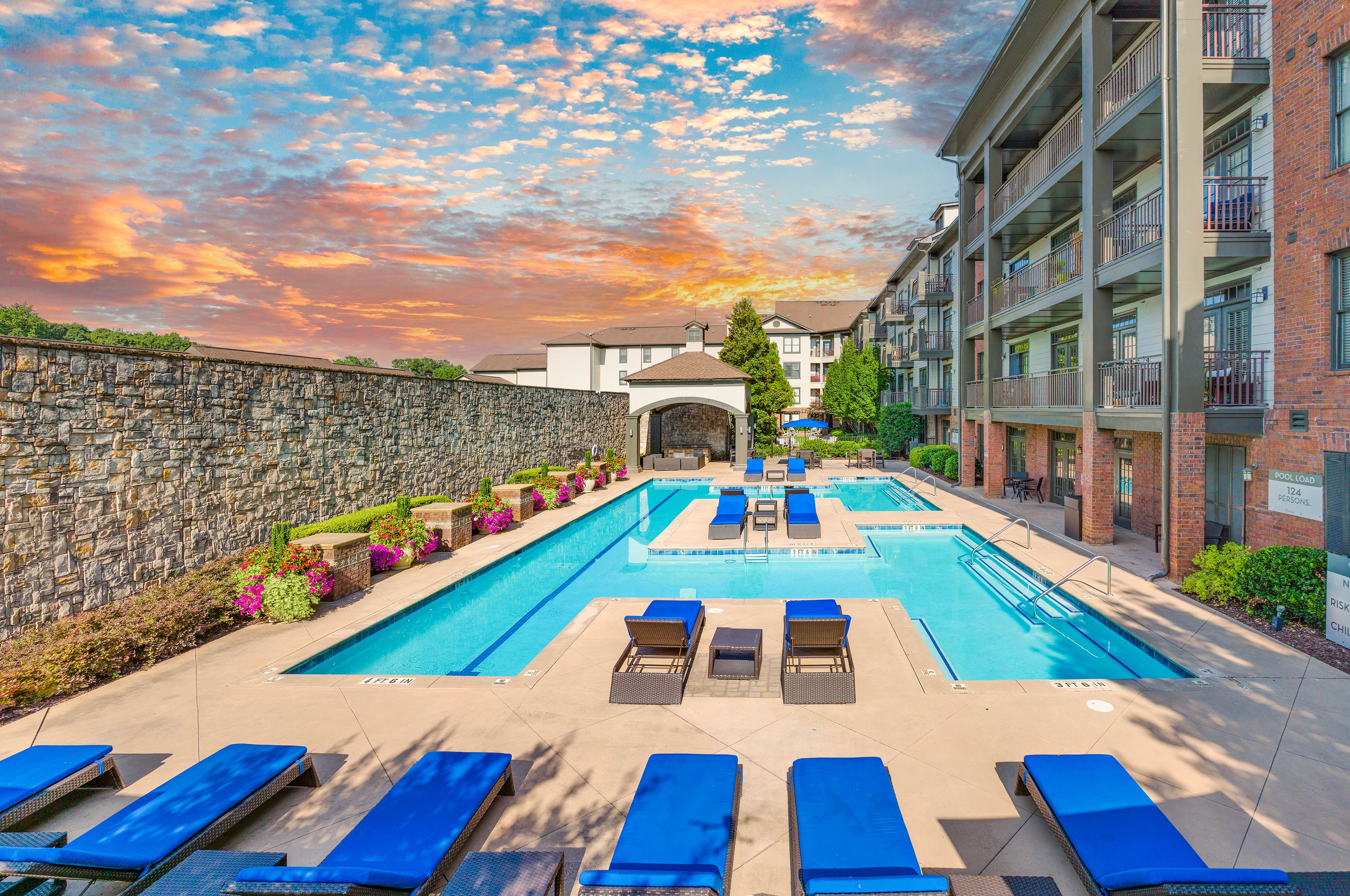 Aerial view of swimming pool with padded blue lounge chairs and lush landscape at MAA West Village luxury apartments in Smyrna, GA