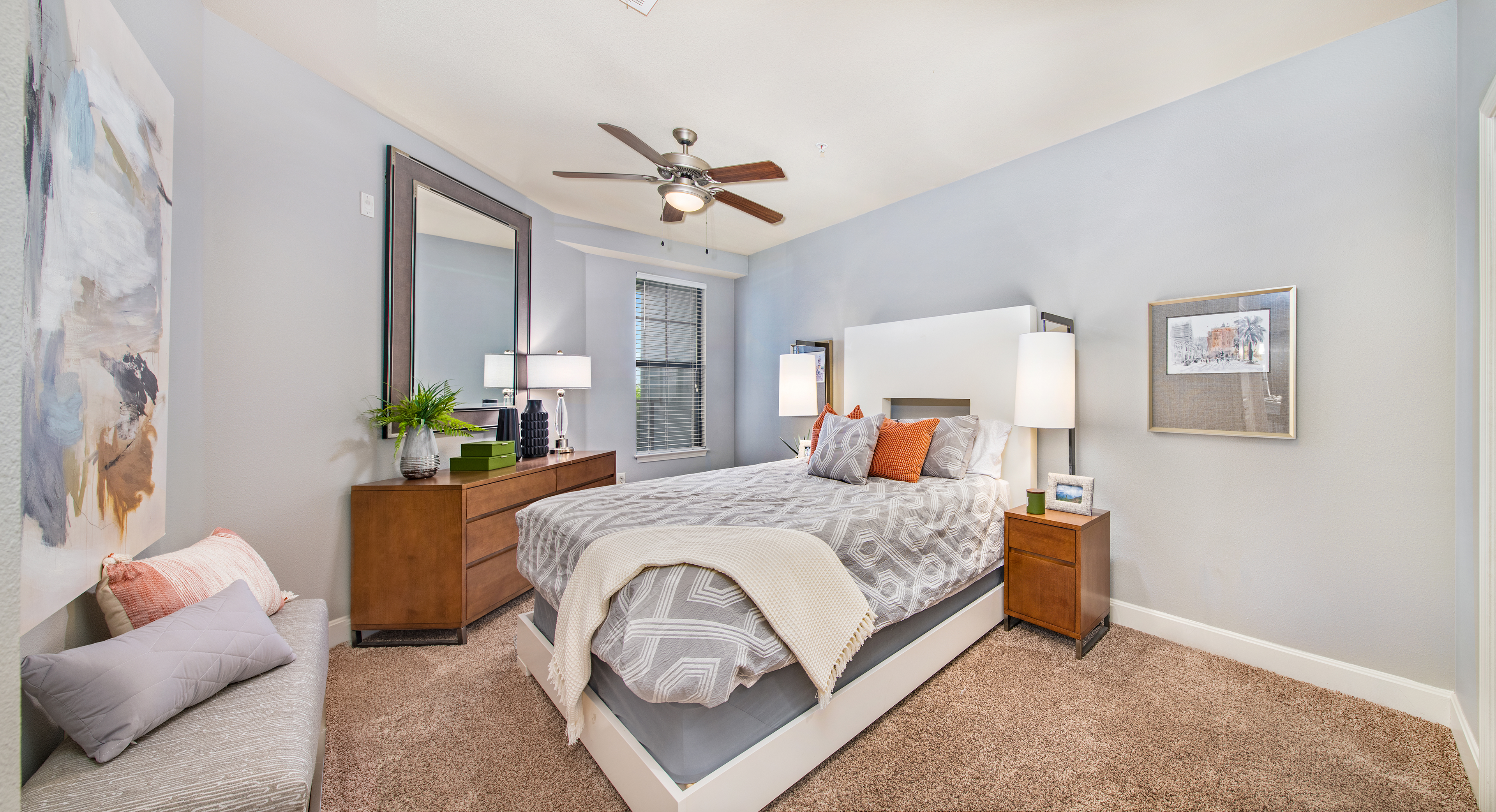 Guest bedroom with wood furniture and ceiling fan at MAA The Station luxury apartments in Kansas City, MO
