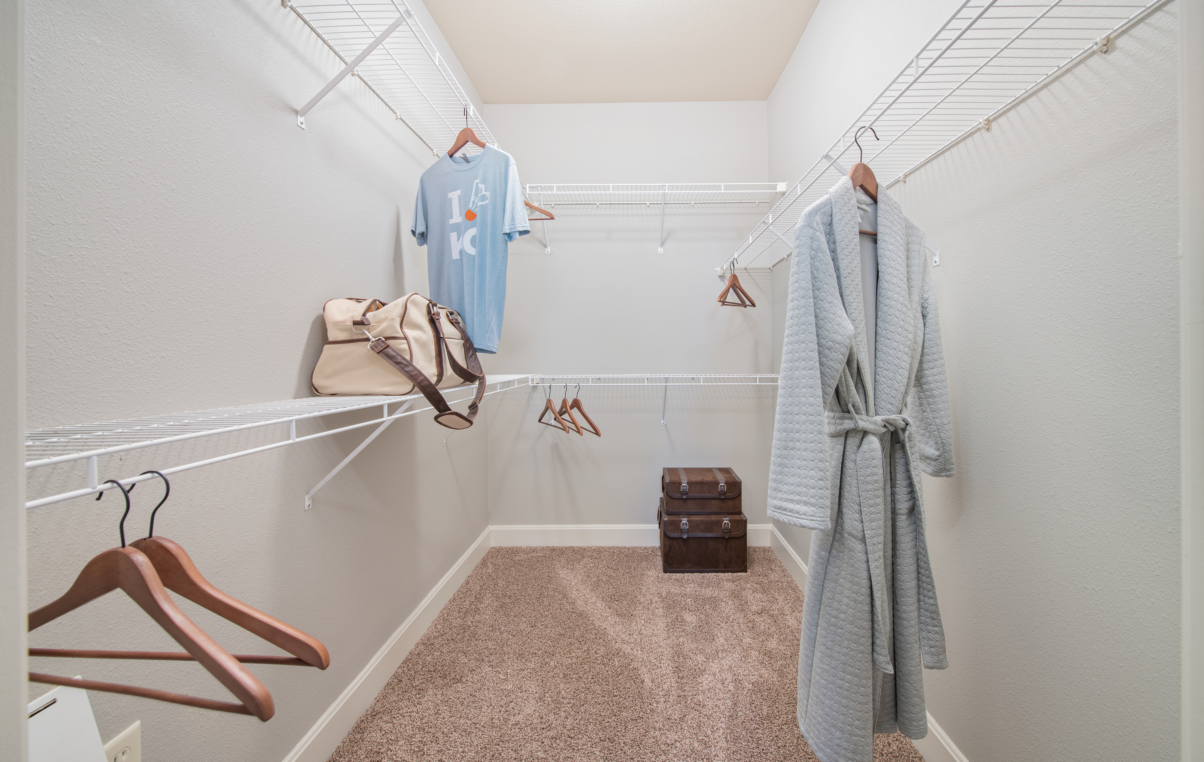 Carpeted walk-in closet with double shelving and storage space at MAA The Station luxury apartments in Kansas City, MO