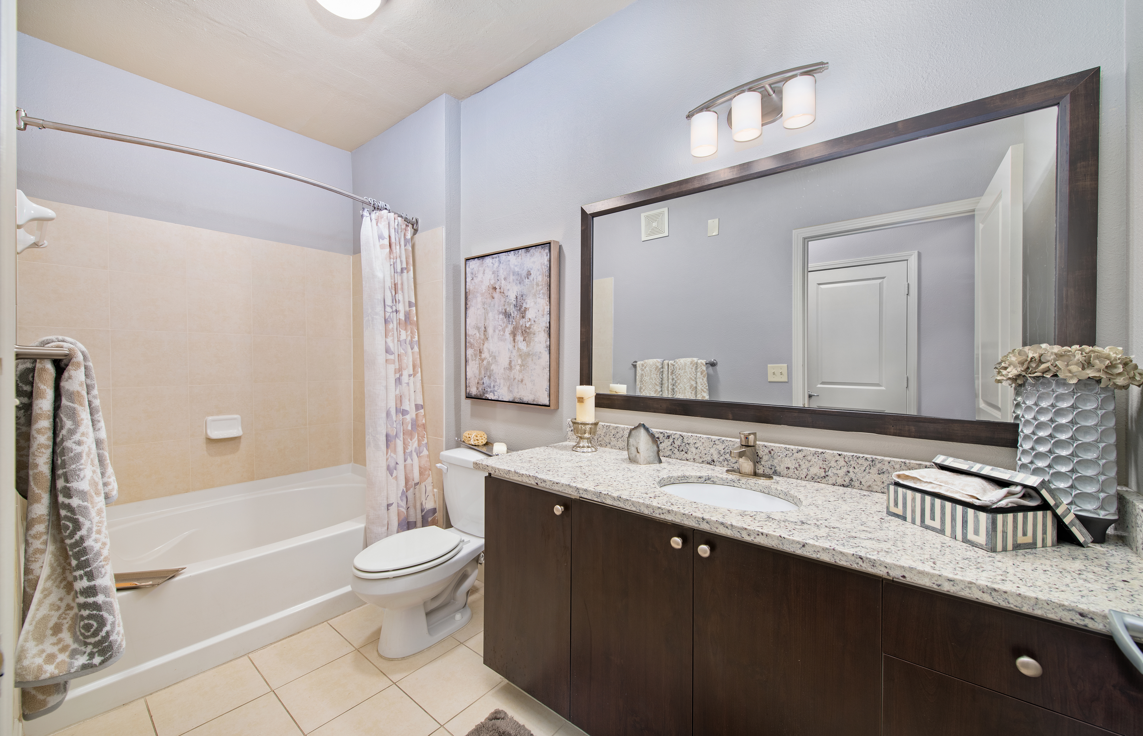 Upscale bathroom with modern wood-accented vanity sink and shower tub at MAA The Station luxury apartments in Kansas City, MO
