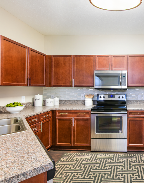 Modern kitchen with wooden cabinets, double sink on granite counter top and stainless steel appliances at MAA Ballantyne luxury apartments in Charlotte, NC