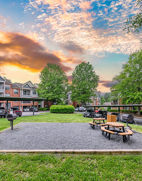 Outdoor grilling area with outside bench seating on gravel at MAA Beverly Crest luxury apartments in Charlotte, NC
