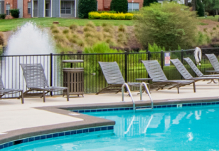 Close up view of gated pool with metal handrails and poolside lounge chairs at MAA Beverly Crest luxury apartments in Charlotte, NC