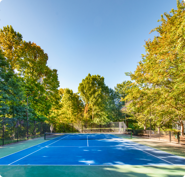 Community tennis court surrounded by lush trees at MAA Chancellor Park luxury apartments in Charlotte, NC