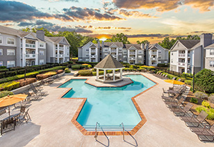 Aerial view of a gated resort-style pool with a gazebo in the pool center, surrounded by lounge chairs and situated on the center of the apartment complex at MAA Chancellor Park luxury apartments in Charlotte, NC