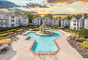Aerial view of a gated resort-style pool with a gazebo in the pool center, surrounded by lounge chairs and situated on the center of the apartment complex at MAA Chancellor Park luxury apartments in Charlotte, NC