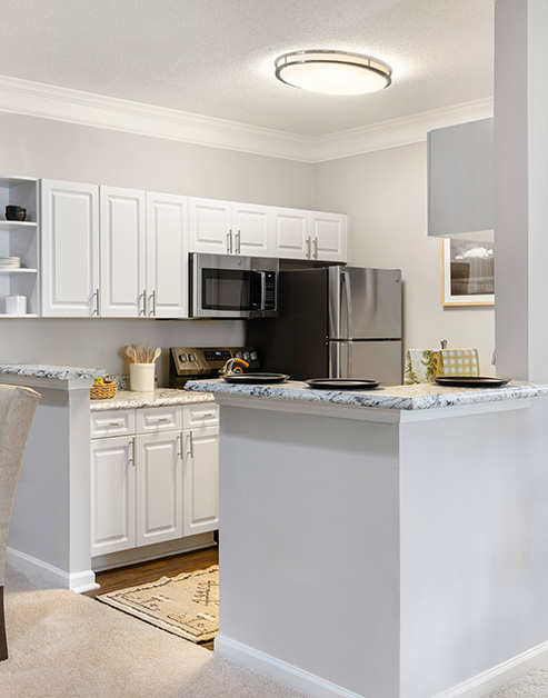 Modern kitchen with white cabinets, upgraded appliances and wood flooring at MAA City Grand luxury apartments in Charlotte, NC