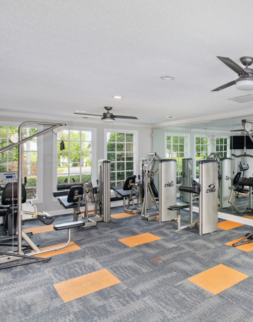 Fitness center with ceiling fans and variety of workout equipment next to large picture windows at MAA City Grand luxury apartments in Charlotte, NC