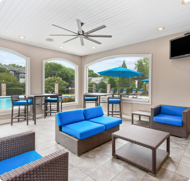 Community clubhouse next to swimming pool with archway open views and multiple seating areas with blue cushions at MAA Cornelius luxury apartments in Cornelius, NC