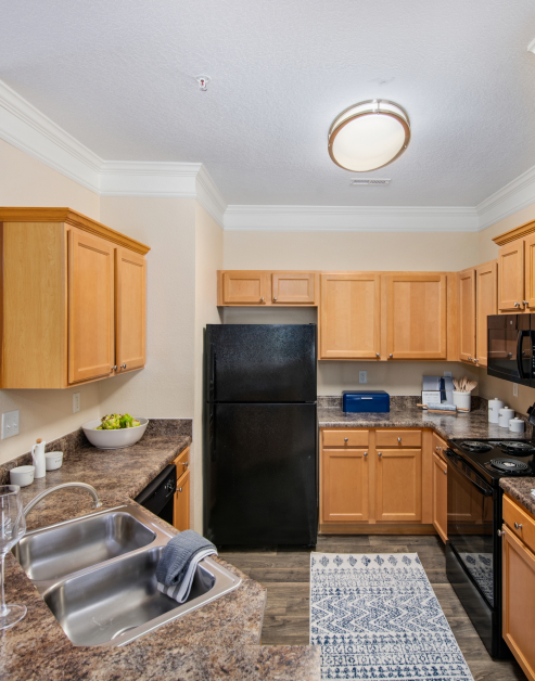 Kitchen with wooden cabinets, double sink on granite countertop and modern appliances at MAA Cornelius luxury apartments in Cornelius, NC