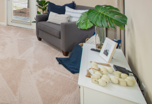 Carpeted living room with modern-style grey sofa with a white cabinet at MAA Cornelius luxury apartments in Cornelius, NC